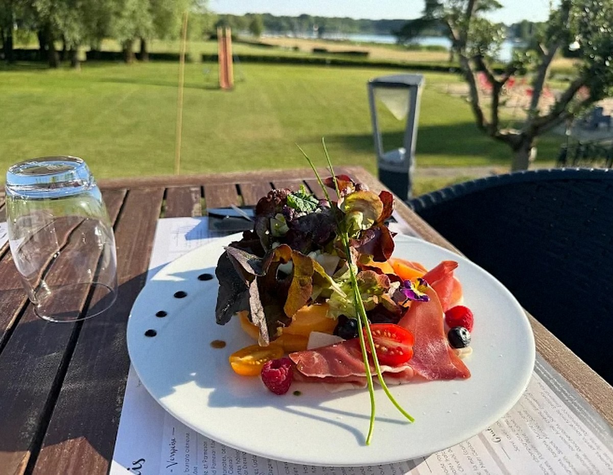 Assiette servie en terrasse au restaurant Les Pâquis, avec vue sur l'étang du Stock à Rhodes